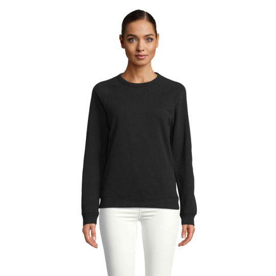Sweat femme personnalisé NELSON noir à col rond porté avec un pantalon blanc, manches raglan et bas en bord côte