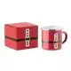 Mug émaillé rouge au décor de costume de Père Noël, ceinture noire et boucle dorée, à côté de sa boîte cadeau assortie