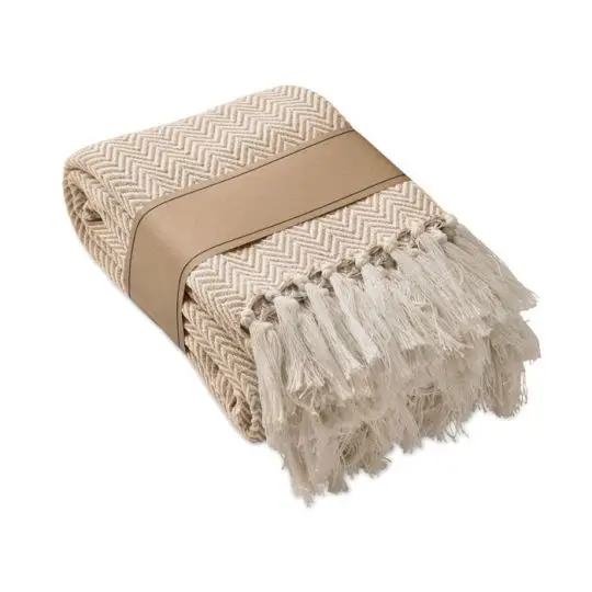 Plaid personnalisé AMMOS beige plié à motif chevrons et franges, présenté dans sa manchette en papier kraft
