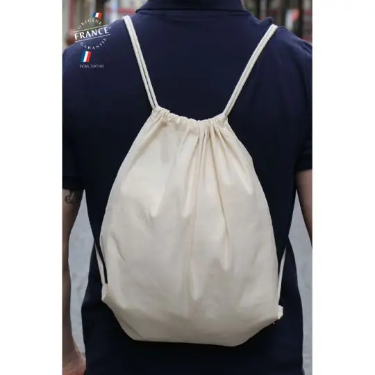 Sac à dos cordelette personnalisé en coton bio écru porté sur le dos d'un homme en t-shirt bleu marine