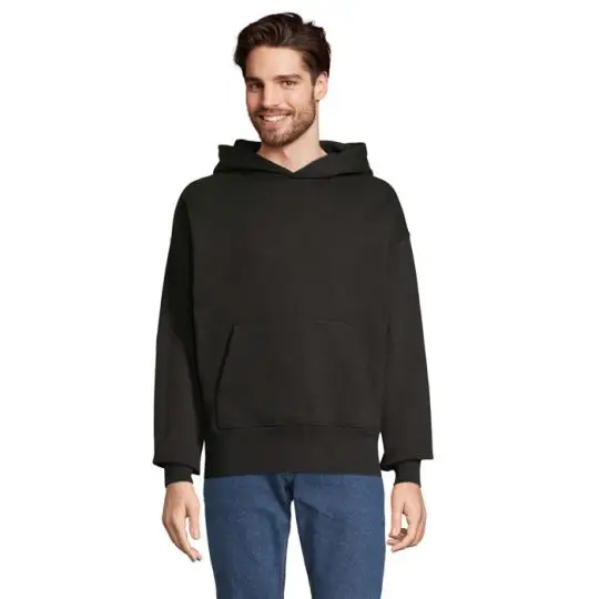 Sweat à capuche oversize personnalisable noir en molleton épais porté de face avec poche kangourou et épaules tombantes