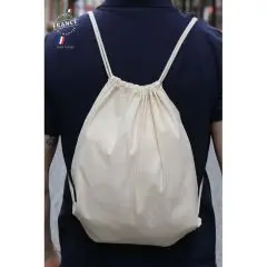 Sac à dos cordelette personnalisé en coton bio écru porté sur le dos d'un homme en t-shirt bleu marine