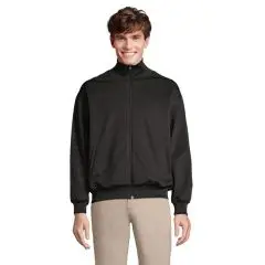 Veste de survêtement personnalisée JUNIOR noire zippée à col montant, portée sur un pantalon beige, vue de face